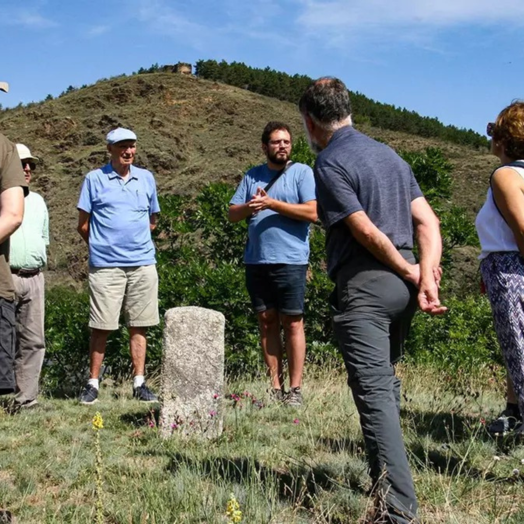 Grup de visitants al voltant d'una fita fronterera durant una visita guiada a l'exterior