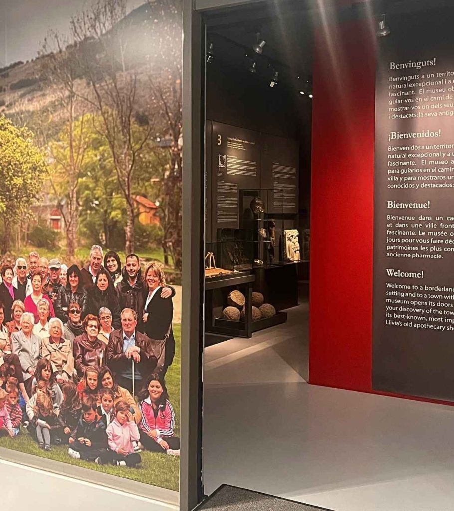 Entrada de l'exposició permanent amb mural fotogràfic de veïns de Llívia i panell de benvinguda multilingüe