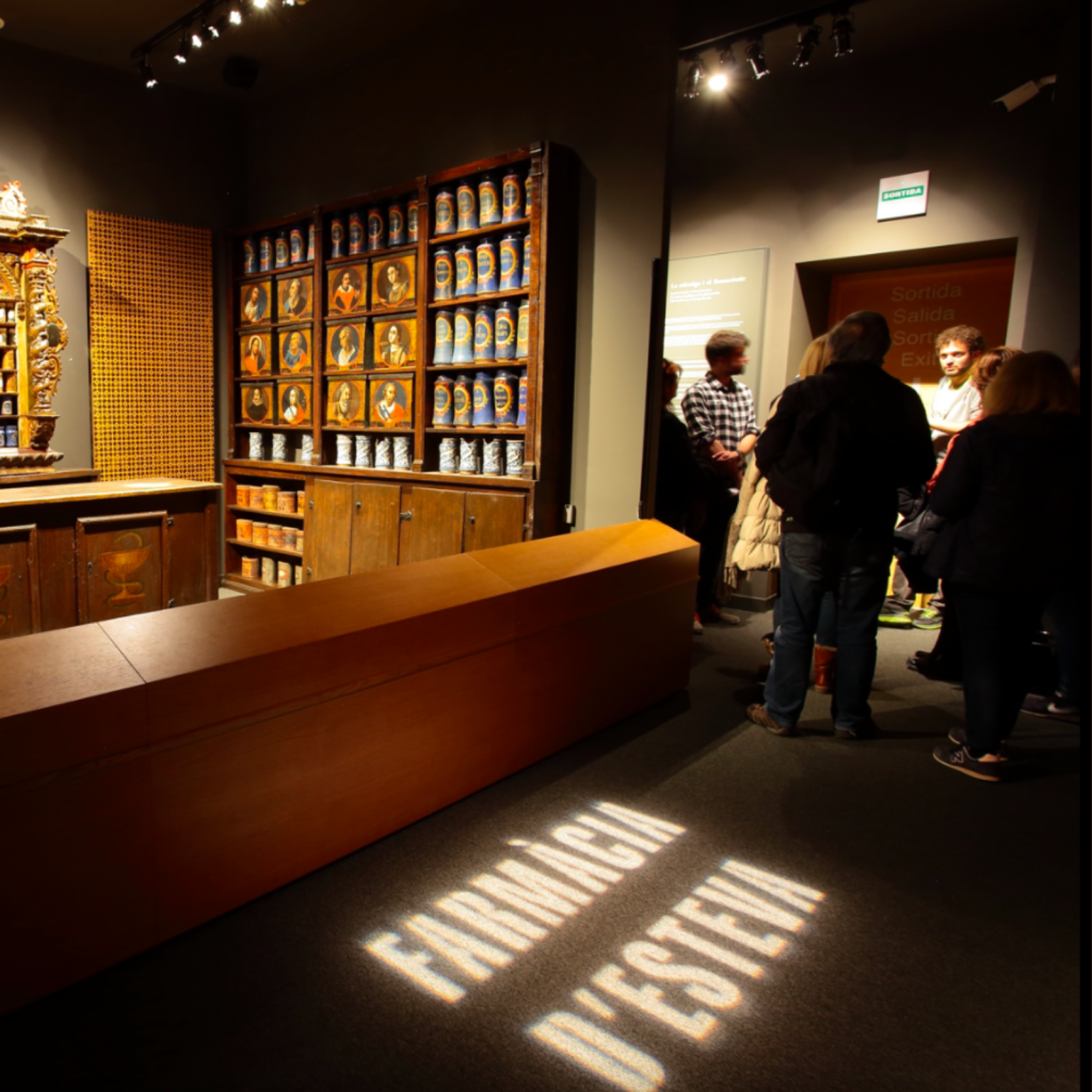 Visitants a la sala d'exposició de la Farmàcia Esteva durant una visita nocturna al museu