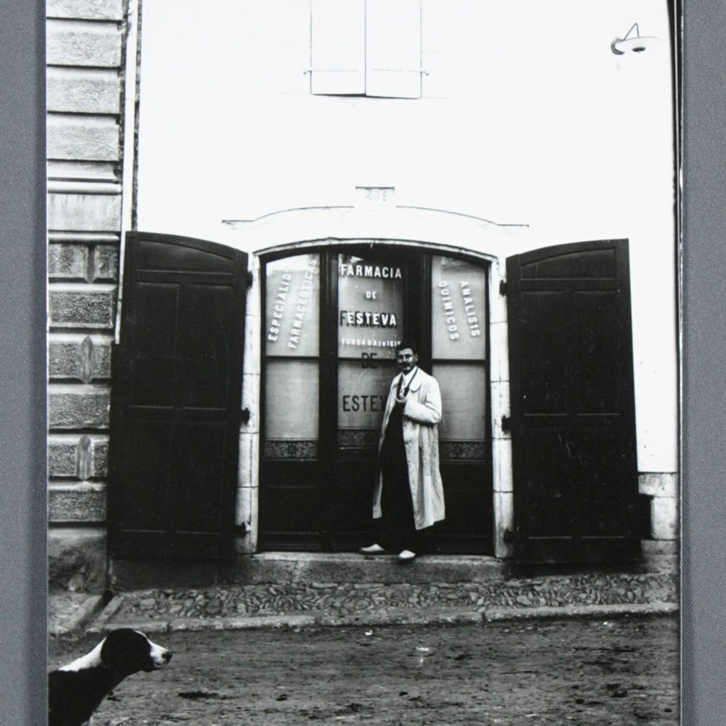 Fotografia històrica de la façana de la Farmàcia de Esteva amb el farmacèutic al portal