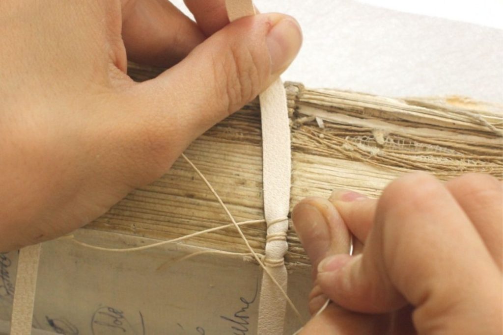 Procés de restauració manual del llibre antic, cosit del llom amb fil